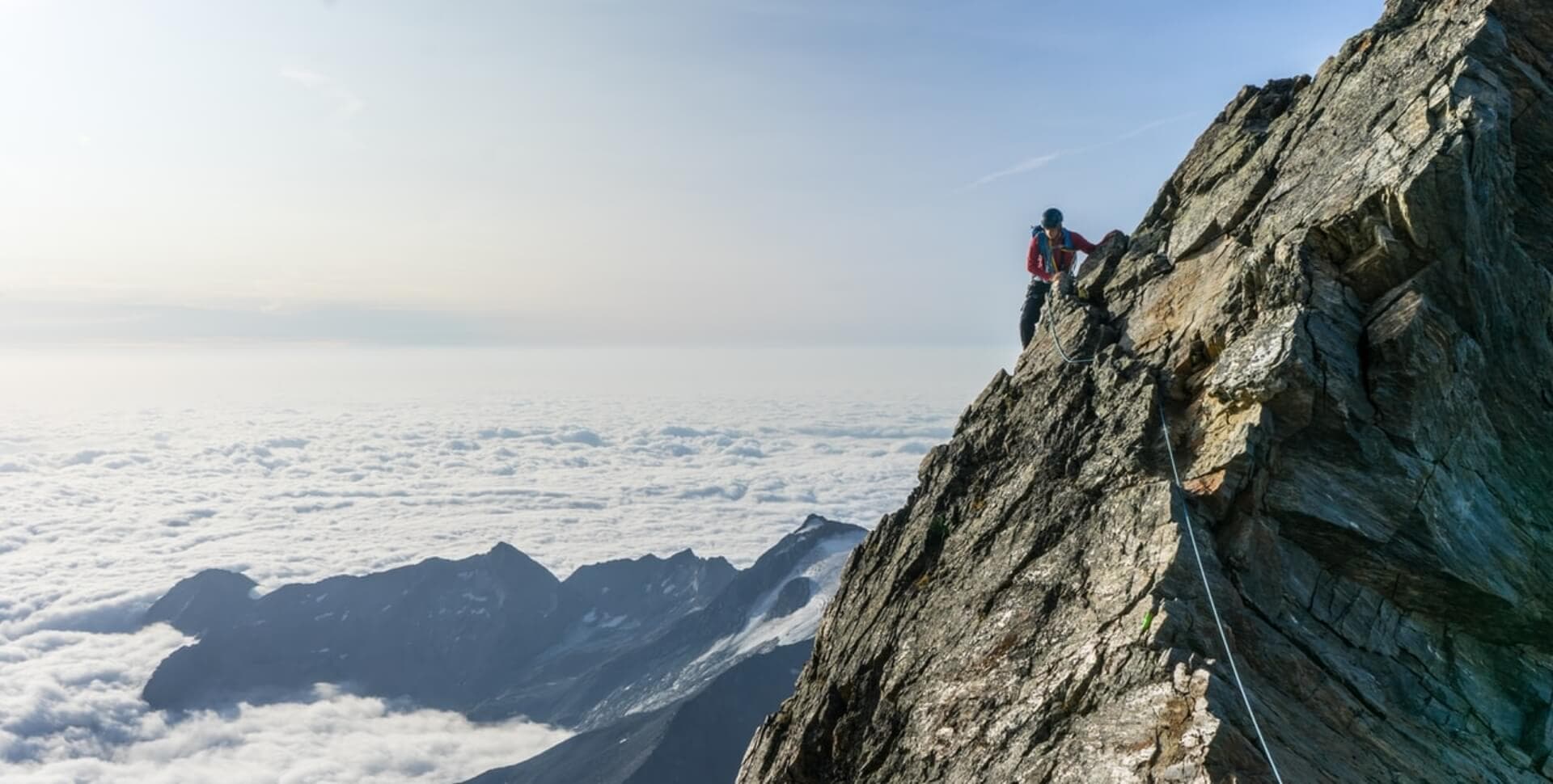 A climber making their way along a Swiss alpine ridge above the clouds